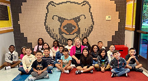 third grade class sitting in front of tile bear art